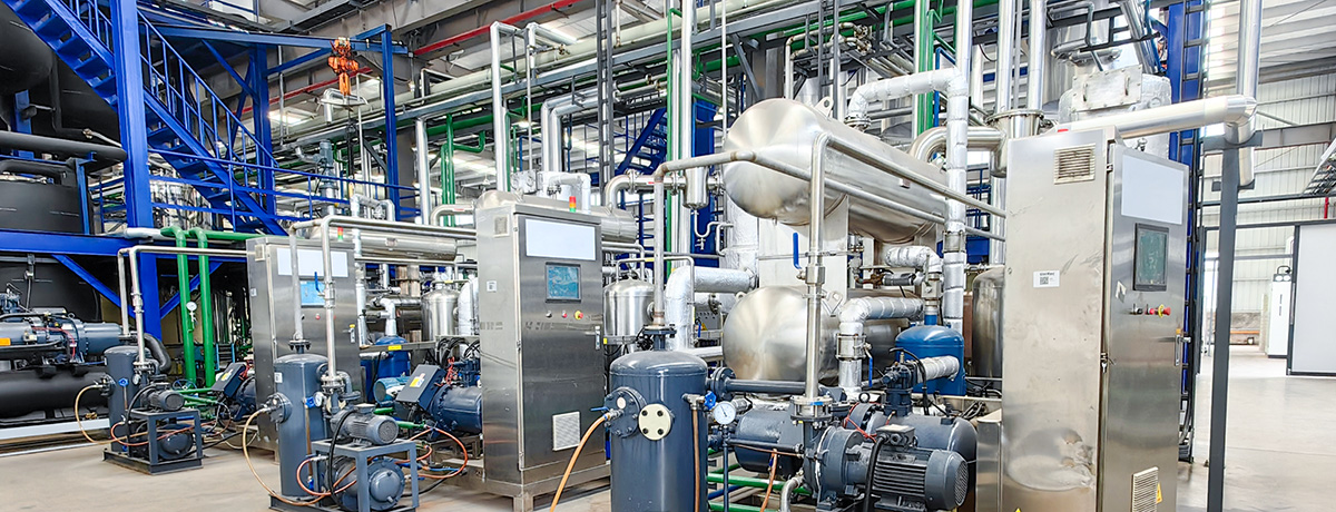 Industrial facility with stainless steel reactors, nutsche filter dryers, vacuum emulsification tanks, mixing tanks, and low temperature evaporators.